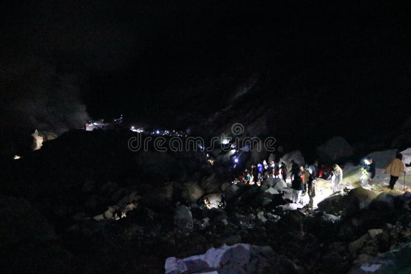 印尼爪哇岛伊根火山 - 2024年2月4日：人们在夜间步行前往火山火山口的蓝色火焰 免版税库存图片