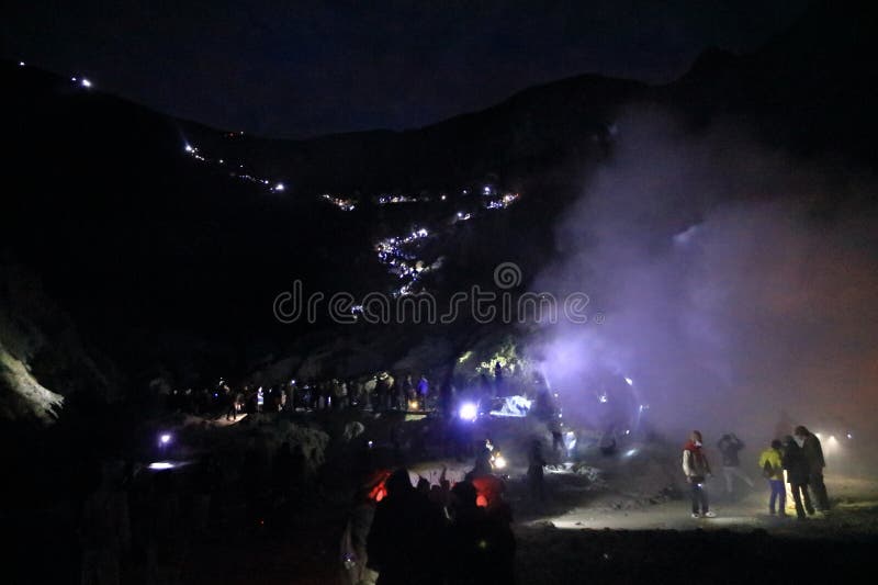 印尼爪哇岛伊根火山 - 2024年2月4日：人们在夜间步行前往火山的蓝色火焰 图库摄影