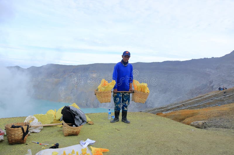 印尼爪哇岛伊真火山 - 2024年2月4日：清晨一位提着硫磺篮子的工人 库存照片