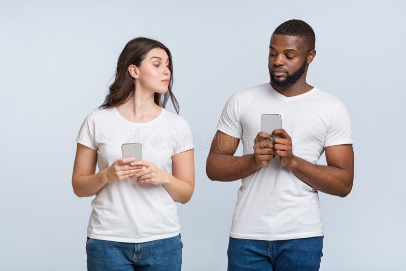 Jealous young woman peeking into her boyfriends phone royalty free stock images Jealous young woman peeking into her boyfriends phone royalty free stock images