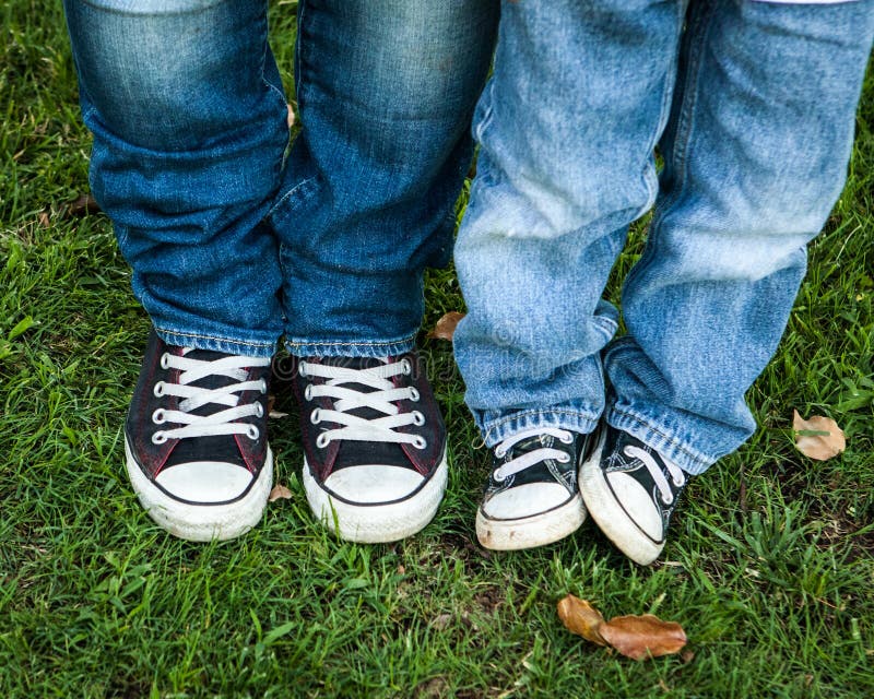 Jeans och svartvita skor vuxen människa och barn arkivbild Jeans och svartvita skor vuxen människa och barn arkivbild