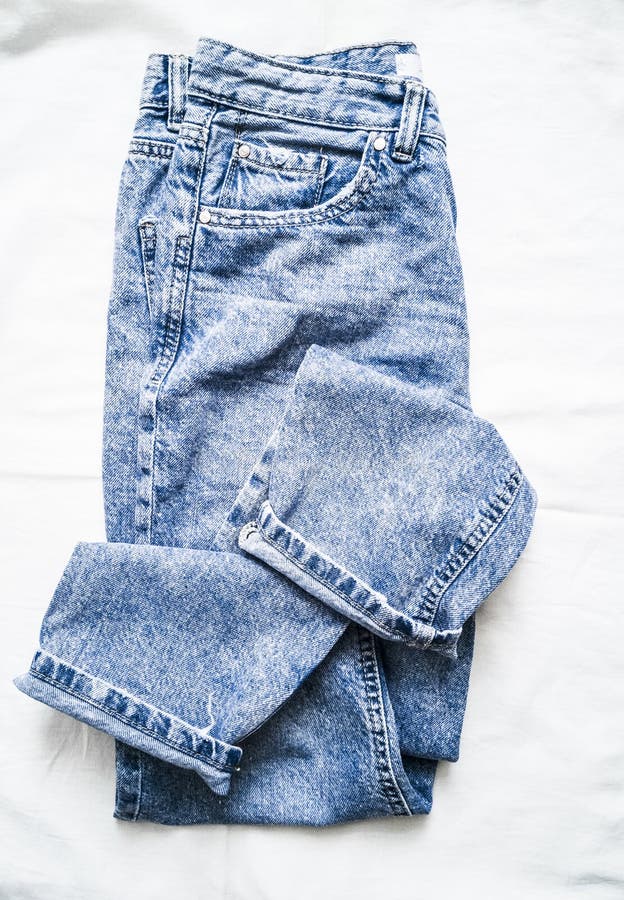 Jeans sbiaditi blu della mamma su un fondo leggero, vista superiore Abbigliamento di modo