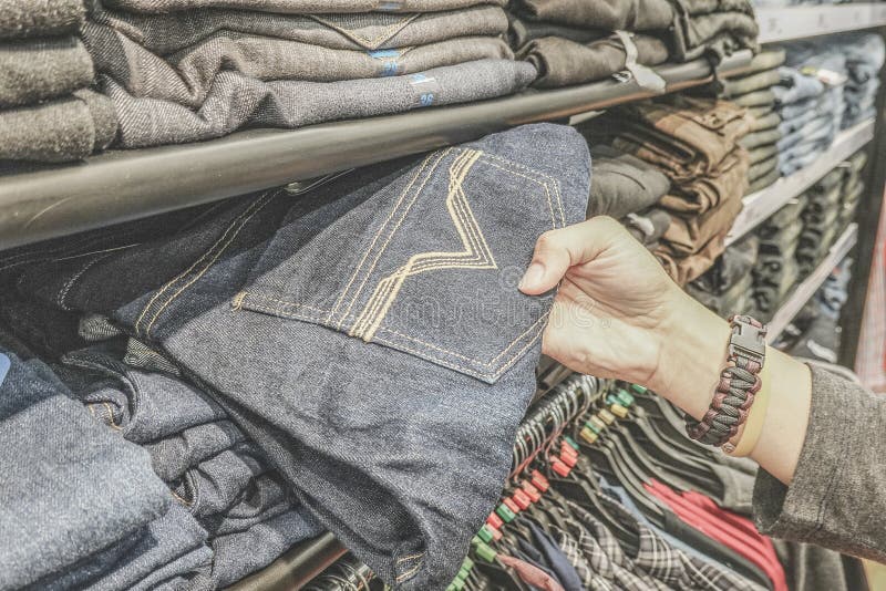 Jeansspeichereinkaufen Regal mit neuen Blue Jeans im Speicher Mannhandkontrolle einige Jeans und irgendein Einzelteil wählen stockfotografie Jeansspeichereinkaufen Regal mit neuen Blue Jeans im Speicher Mannhandkontrolle einige Jeans und irgendein Einzelteil wählen stockfotografie