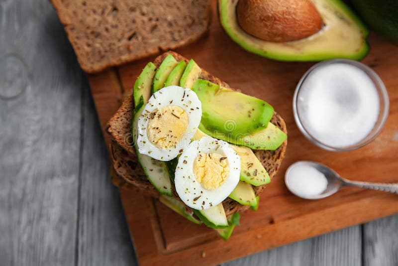 jeden avocado i kanapki z jajkiem i pikantność na drewnianej desce zdjęcie stock jeden avocado i kanapki z jajkiem i pikantność na drewnianej desce zdjęcie stock