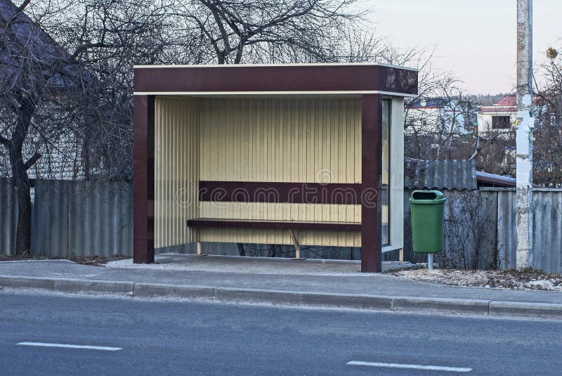 Jeden brązowy plastikowy i metalowy przystanek autobusowy jest otwarty na ulicy miejskiej