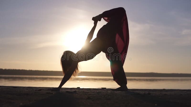 Jeden caucasian kobieta ćwiczy joga outdoors Sylwetka odizolowywająca na morzu na tle i zmierzchu