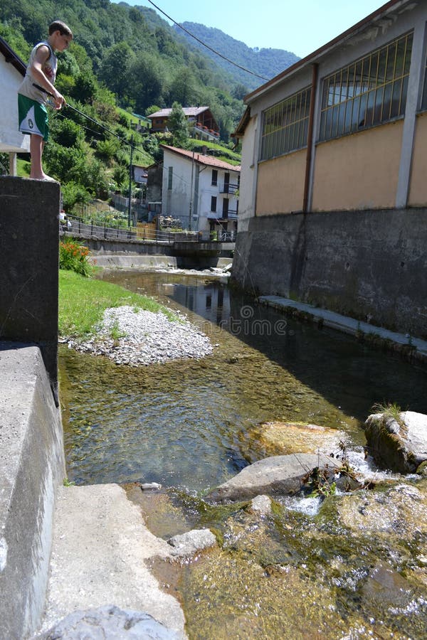 Lecco/Italy - August 1, 2013: One boy is fishing in the mountain stream with fishing rod. Lecco/Italy - August 1, 2013: One boy is fishing in the mountain stream with fishing rod.