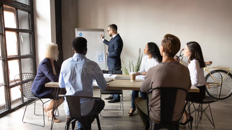 Boss stands near flip chart presents topic to audience, demonstrate stats, diverse staff attending at training, introduction of new idea or company products, reporting work result for partners concept. Boss stands near flip chart presents topic to audience, demonstrate stats, diverse staff attending at training, introduction of new idea or company products, reporting work result for partners concept