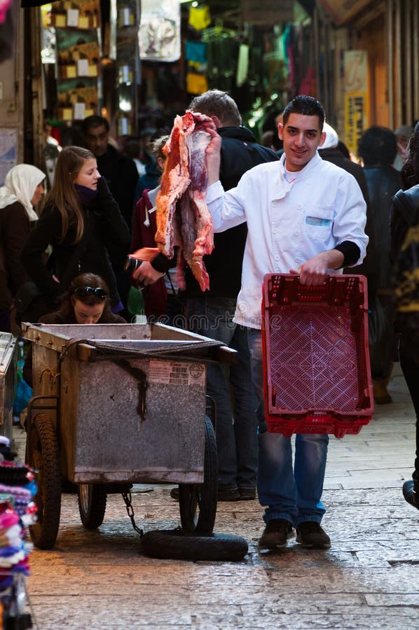 Jerusalém, em dezembro de 2012: O carniceiro novo troca a carne no souk do Jerusalém foto de stock royalty free Jerusalém, em dezembro de 2012: O carniceiro novo troca a carne no souk do Jerusalém foto de stock royalty free