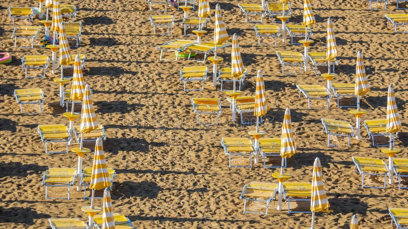 Jesolo italia. ombrelli da spiaggia e letti solari sulla spiaggia italiana di sandy. razze di ombrelli gialli e bianchi. vista aer immagini stock