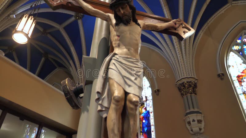 Jesus christ sobre la estatua de cruz bajo el techo azul real en la iglesia católica