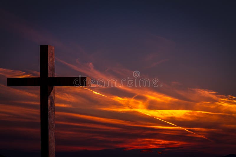 Jesus Christ wooden cross on a background with dramatic, colorful sunset, and orange, purple sky. Jesus Christ cross. Christian wooden cross on a background with royalty free stock image