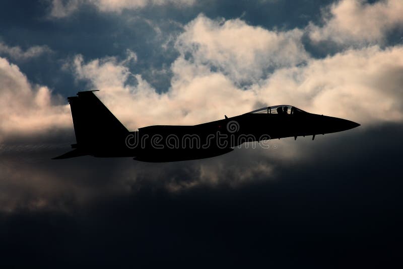 Military supersonic jet fighter at sunset with dark clouds in the background