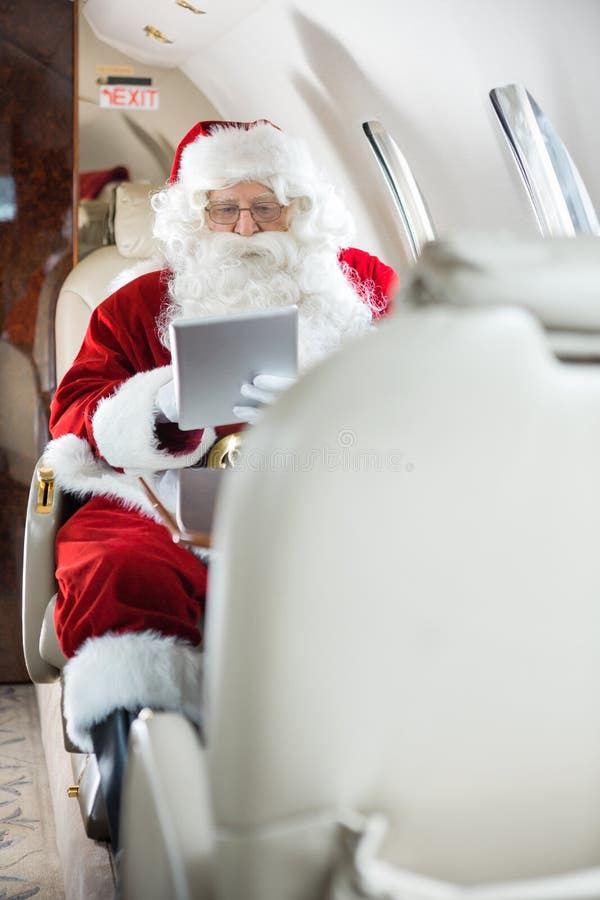 Jet privé de Santa Using Tablet Computer In photo libre de droits Jet privé de Santa Using Tablet Computer In photo libre de droits