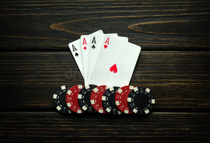 Chips and playing cards with a winning combination of four of a kind or quads on a black vintage table. Concept of winning in a poker club or casino. Chips and playing cards with a winning combination of four of a kind or quads on a black vintage table. Concept of winning in a poker club or casino.