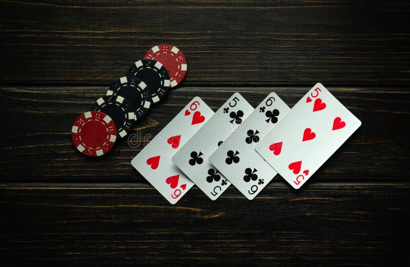 Black and red chips and playing cards with a winning combination of two pairs on a dark vintage table. Low key concept of winning in a poker club or casino. Black and red chips and playing cards with a winning combination of two pairs on a dark vintage table. Low key concept of winning in a poker club or casino.