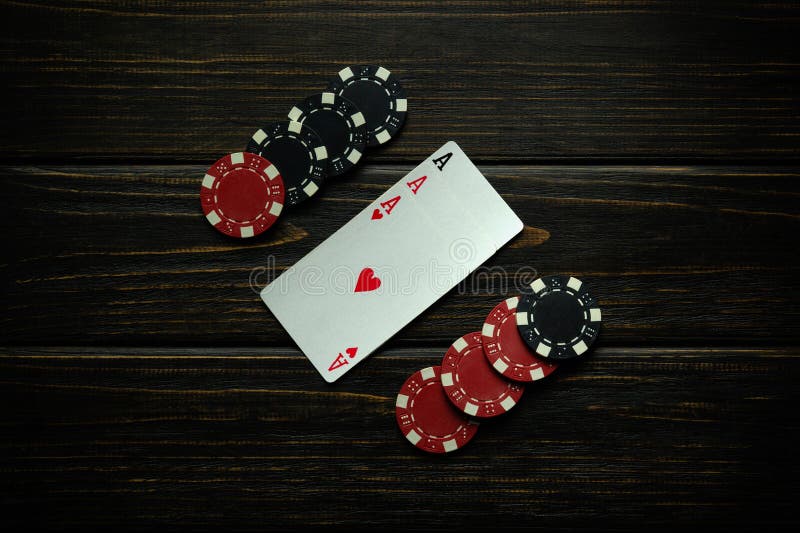 Black and red chips and playing cards with a winning combination of three kind or set on a black vintage table. Concept of winning in a poker club or casino with three aces. Black and red chips and playing cards with a winning combination of three kind or set on a black vintage table. Concept of winning in a poker club or casino with three aces.