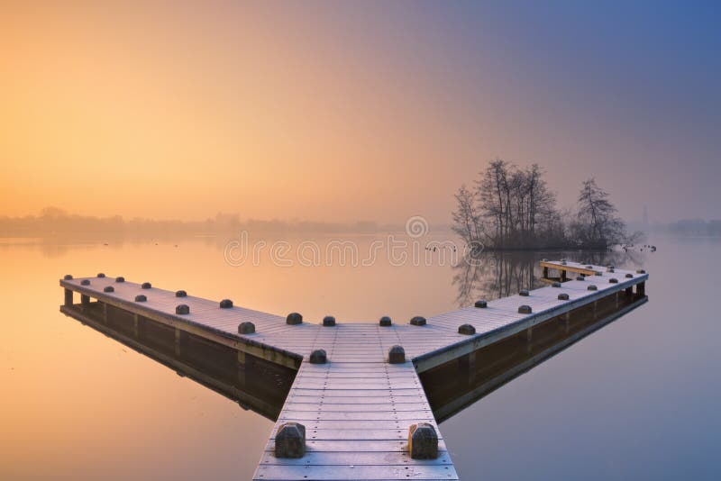 Jetty on a still lake on a foggy winter s morning