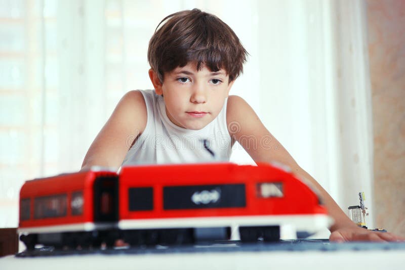 Jeu beau de la préadolescence de garçon avec le train de jouet de meccano et le sta de chemin de fer photographie stock Jeu beau de la préadolescence de garçon avec le train de jouet de meccano et le sta de chemin de fer photographie stock