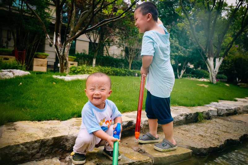 Jeu d'enfants dans le jardin avec des armes à feu et des fusils de l'eau images libres de droits Jeu d'enfants dans le jardin avec des armes à feu et des fusils de l'eau images libres de droits