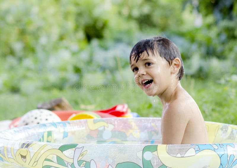 Beautiful little boy playing with water from the pool on a summer day. Beautiful little boy playing with water from the pool on a summer day