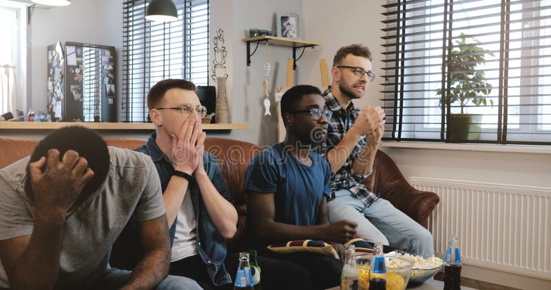 Jeu de observation de sports déçu par hommes ethniques multi les fans 4K geeky passionnées deviennent émotives et tristes Perte e photographie stock Jeu de observation de sports déçu par hommes ethniques multi les fans 4K geeky passionnées deviennent émotives et tristes Perte e photographie stock