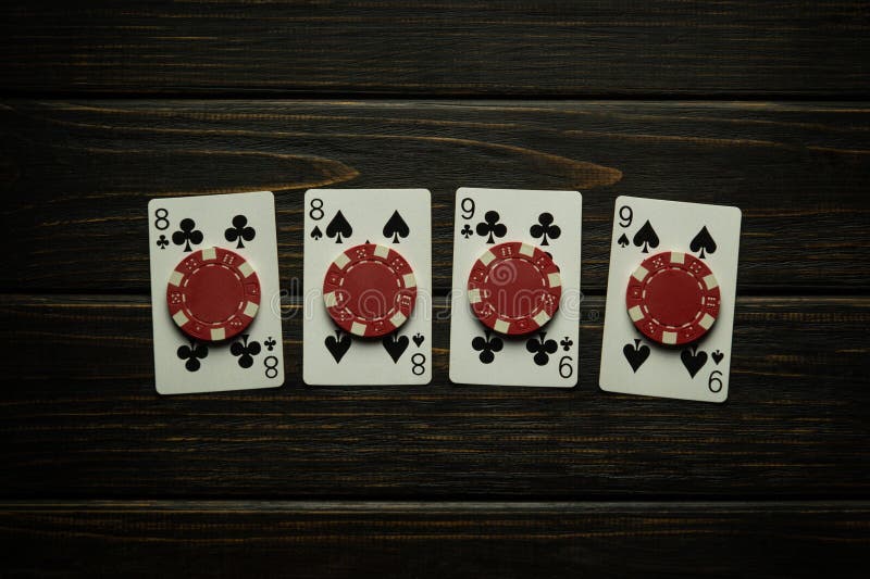 Gambling game of poker with a successful winning combination of two pairs. Playing cards and chips on a black vintage table in a men club. Gambling game of poker with a successful winning combination of two pairs. Playing cards and chips on a black vintage table in a men club.