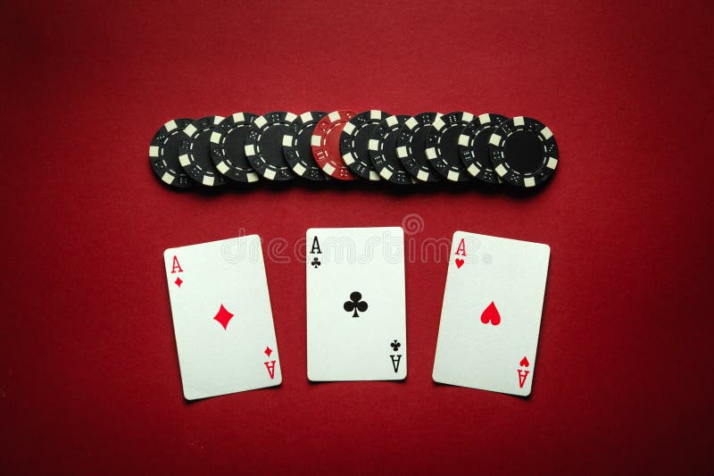 Poker game with a winning combination of three of a kind or set. Playing cards and chips on a red table in a poker club. Winning at a casino depends on luck. Poker game with a winning combination of three of a kind or set. Playing cards and chips on a red table in a poker club. Winning at a casino depends on luck.