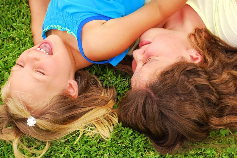 Two caucasian sisters playing and laughing in the grass. Two caucasian sisters playing and laughing in the grass