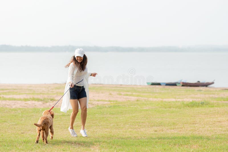 Jeu et fonctionnement asiatiques de femme de mode de vie avec le chien d'amiti? de golden retriever dans le lever de soleil ext?r photographie stock libre de droits Jeu et fonctionnement asiatiques de femme de mode de vie avec le chien d'amiti? de golden retriever dans le lever de soleil ext?r photographie stock libre de droits