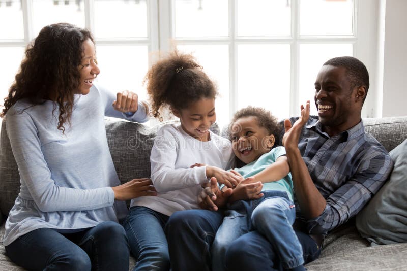 Jeu riant de famille noire heureuse chatouillant des enfants à la maison