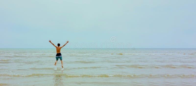 Jeune adolescent heureux en pantalon nageant sauter au-dessus de la plage tropicale chaam en thaïlande. photographie stock libre de droits