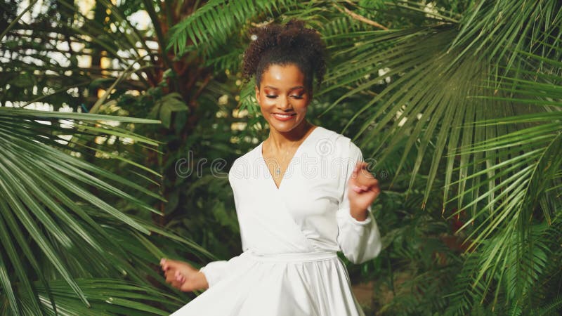 Jeune adulte heureuse Africaine Américaine marchant dans la forêt tropicale dansant tournoyant dans des feuilles de palmier vert s banque de vidéos