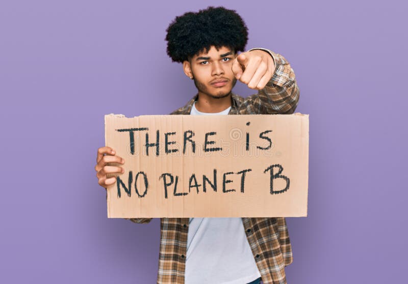 Jeune afro-américain avec cheveux afro tenant il n'y a pas de planète b bannière pointant du doigt vers l'appareil photo et vers v image stock