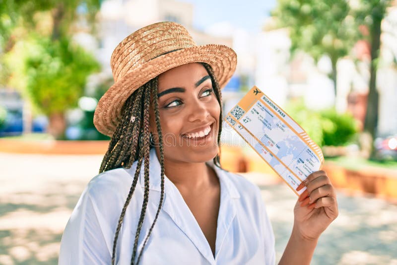 Jeune afro-américaine avec des tresses souriant joyeuse tenue d'embarquement passe à l'extérieur par une journée ensoleillée d'été photographie stock libre de droits