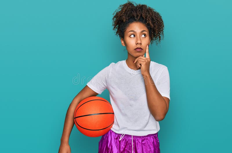 Jeune afro-américaine jouant au baseball tenant chauve-souris et balle grave visage penser à la question avec la main sur le mento photo libre de droits