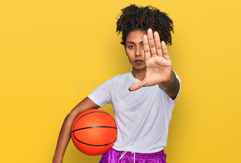 Jeune afro-américaine jouant au baseball tenant chauve-souris et balle à main ouverte faisant stop signe avec sérieux et confiant photos stock