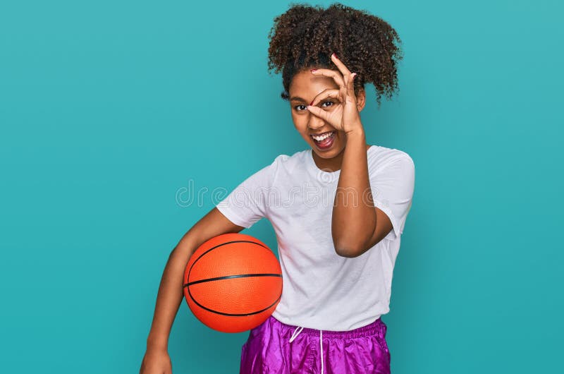 Jeune afro-américaine jouant au baseball tenant la batte et la balle souriant heureux faisant ok signe avec main sur oeil à traver image stock
