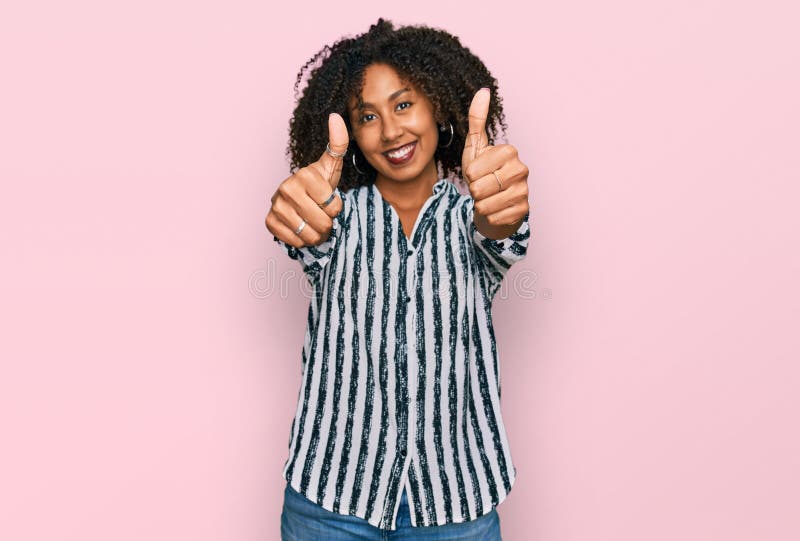 Jeune afro-américaine portant des vêtements décontractés approuvant faire un geste positif avec les pouces à la main souriant et h photographie stock