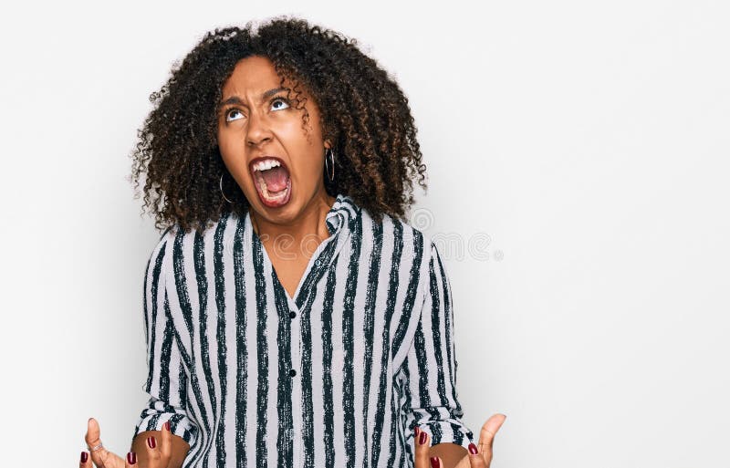 Jeune afro-américaine portant des vêtements décontractés fou et fou criant et hurlant avec une expression agressive et les bras le photos libres de droits