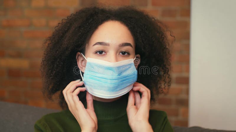 Jeune afro-américaine portant un masque médical de protection avant de sortir grand portrait ralenti banque de vidéos