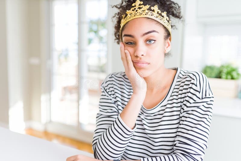 Jeune afro-américaine portant une couronne de reine d'or sur la tête, pensant fatigué et ennuyé avec des problèmes de dépression image libre de droits