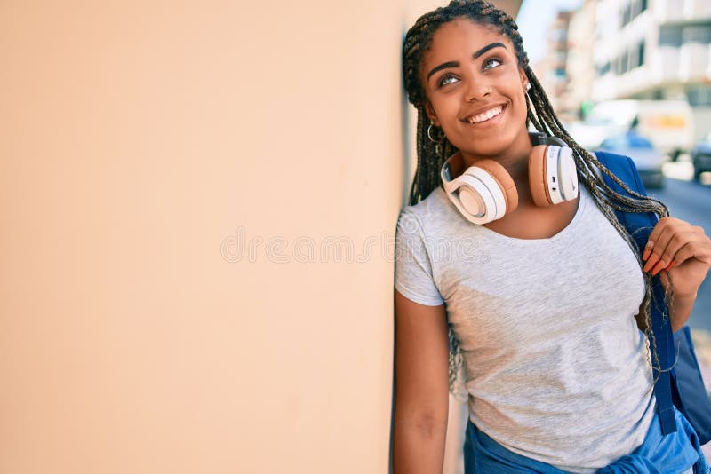 Jeune afro-américaine étudiante souriante heureuse assise sur le mur du campus universitaire photographie stock libre de droits