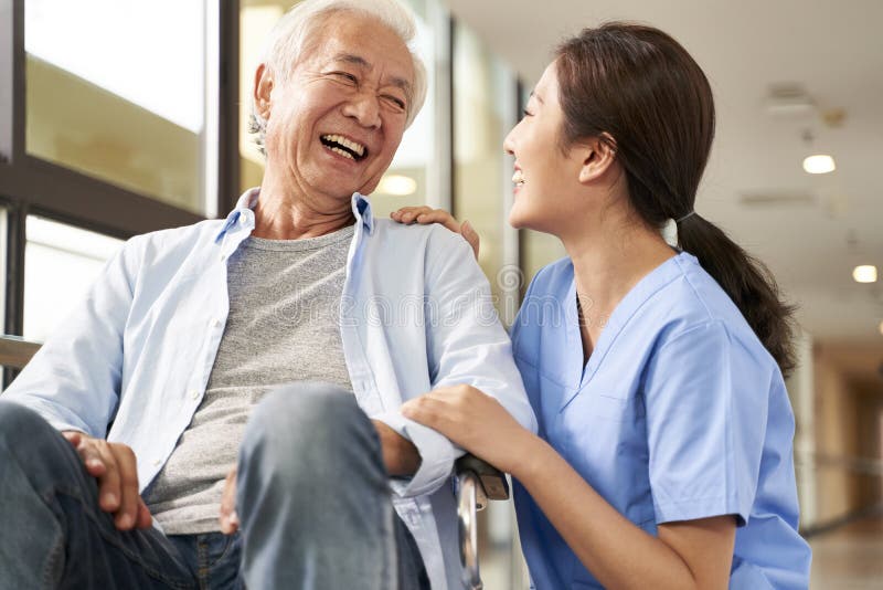 Jeune amicale asiatique aide-soignante femme parler à un homme âgé dans une maison de soins infirmiers