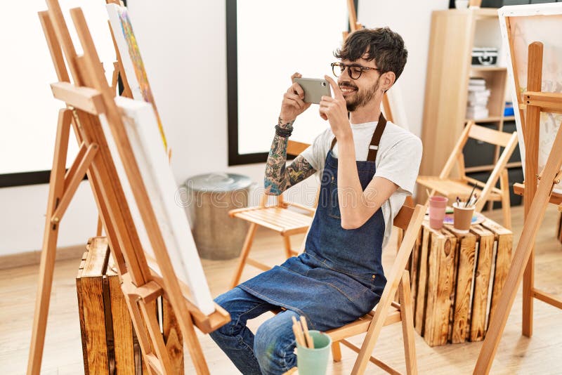Jeune artiste hispanique homme faire une photo à l'aide de smartphone dessin au studio art