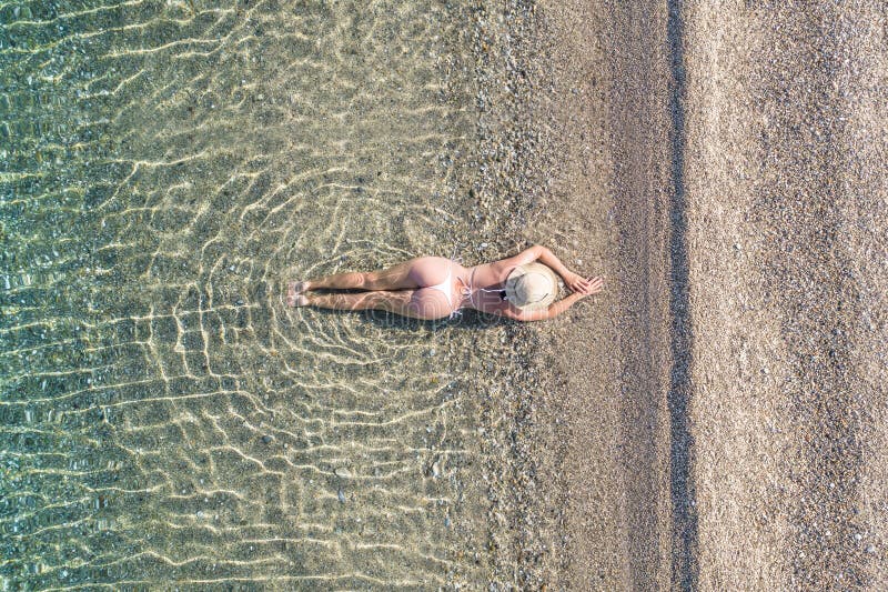 Jeune athlète en maillot de bain allongé et bronzer dans l'eau de mer sur la plage de sable. été. vue depuis le haut. ordinateur à photographie stock libre de droits