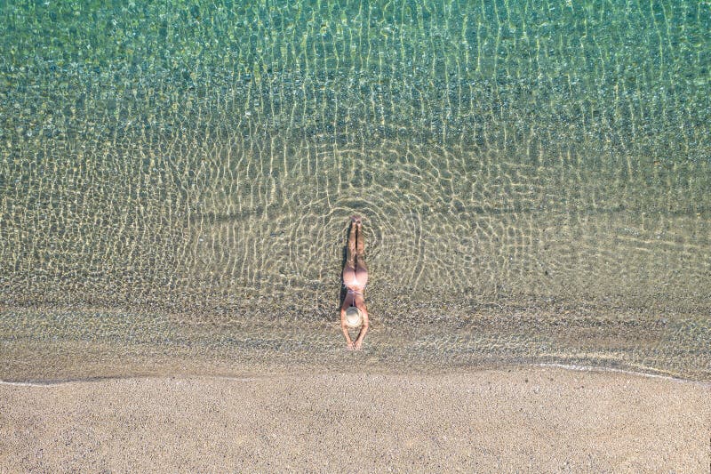 Jeune athlète en maillot de bain allongé et bronzer dans l'eau de mer sur la plage de sable. été. vue depuis le haut. ordinateur à vue supérieure.