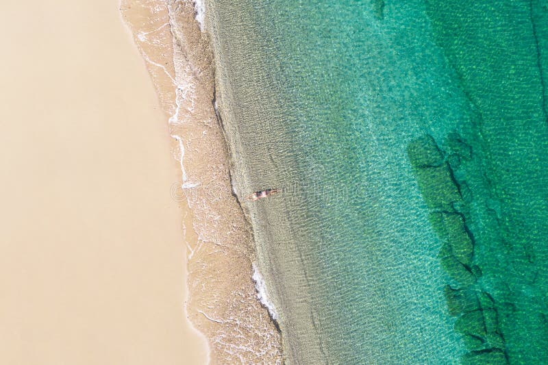 Jeune athlète en maillot de bain allongé et bronzer dans l'eau de mer sur la plage de sable. été. vue depuis le haut. ordinateur à photos stock