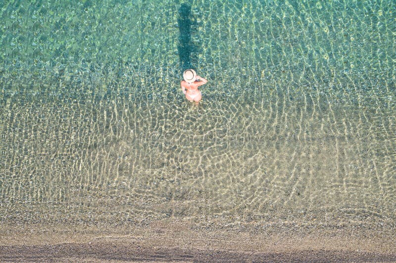 Jeune athlète en maillot de bain et chapeau entrant en mer sur la plage de sable. été. vue depuis le haut. ordinateur à vue supéri images stock