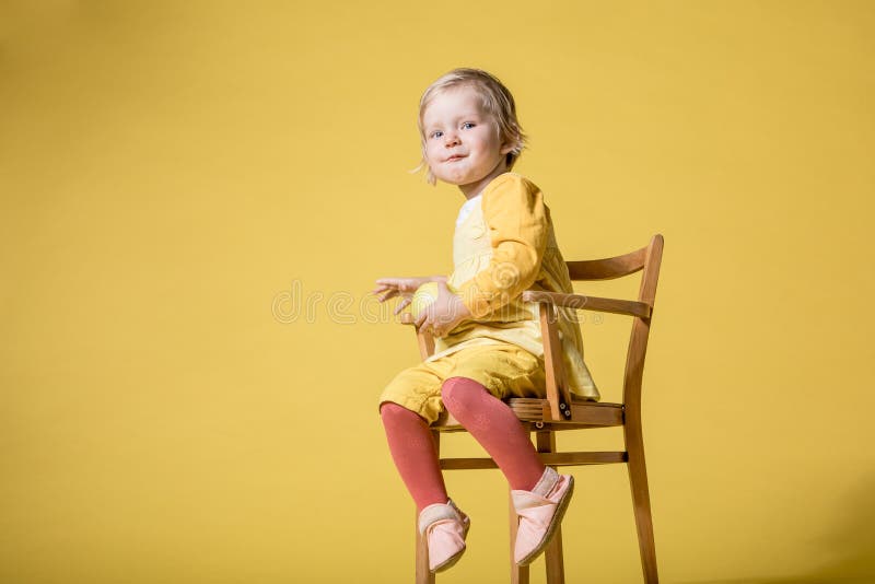 Jeune b?b? dans la robe jaune sur le fond jaune photo libre de droits Jeune b?b? dans la robe jaune sur le fond jaune photo libre de droits